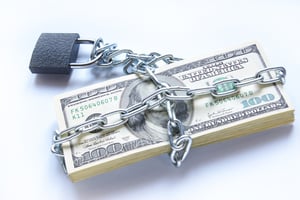 A neat stack of one hundred dollar bills chained up and locked.